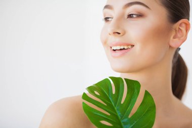 Spa bakımı. Büyük yeşil yapraklı genç güzel esmer kadın