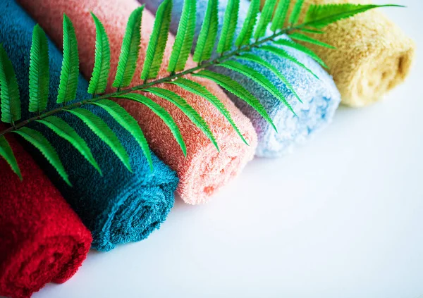 Toallas de colores y hojas de helecho en mesa blanca con espacio para copiar en el fondo de la sala de baño . — Foto de Stock