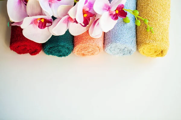 Toallas coloreadas y orquídea en mesa blanca con espacio de copia en el fondo del cuarto de baño . — Foto de Stock