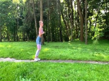 Sağlıklı bir yaşam tarzı. Orman yolunda koşan bir kadın. Yavaş çekim.