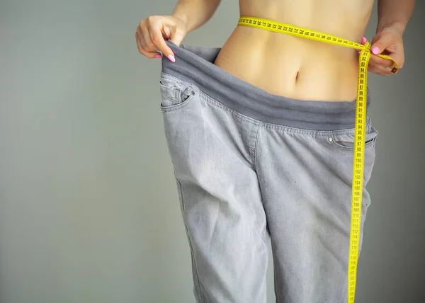 Mains mesurant la taille avec un ruban adhésif. Femme mince et en bonne santé à sa maison — Photo