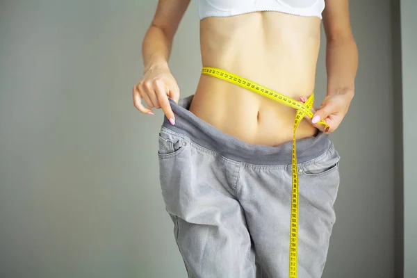 Mains mesurant la taille avec un ruban adhésif. Femme mince et en bonne santé à sa maison — Photo