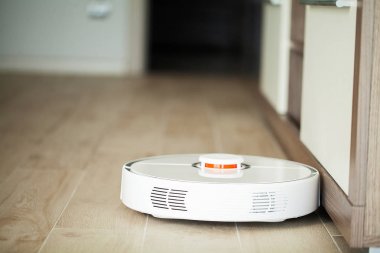 Akıllı Ev. Elektrikli süpürge robotu oturma odasında ahşap zeminde koşar..