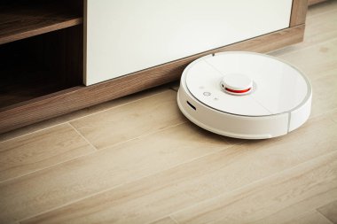 Akıllı Ev. Elektrikli süpürge robotu oturma odasında ahşap zeminde koşar..