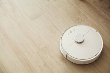 Akıllı Ev. Elektrikli süpürge robotu oturma odasında ahşap zeminde koşar..