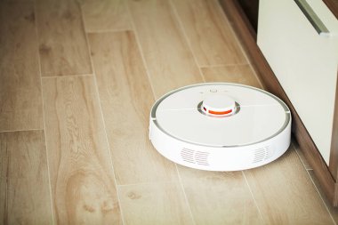 Akıllı Ev. Elektrikli süpürge robotu oturma odasında ahşap zeminde koşar..