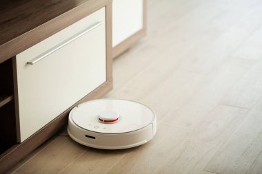 Akıllı Ev. Elektrikli süpürge robotu oturma odasında ahşap zeminde koşar..
