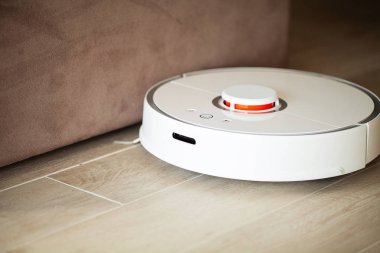 Akıllı Ev. Elektrikli süpürge robotu oturma odasında ahşap zeminde koşar..