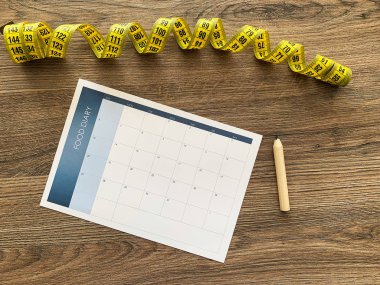 Diyet planı kavramı. Ahşap arka planda bant ve diyet planının ölçülmesi.