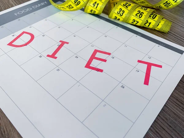 Diet plan concept. Measuring tape and diet plan on wooden background
