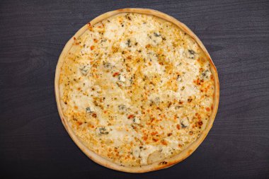 Koyu bir arka plan üzerinde çeşitli aromalı malzemelerle lezzetli pizza