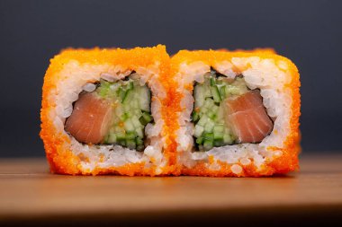 Koyu arka planda somon ve salatalık ile California rulo.