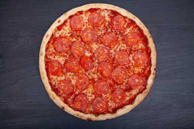 Koyu bir arka plan üzerinde çeşitli aromalı malzemelerle lezzetli pizza