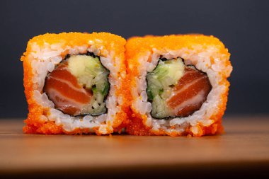 Koyu arka planda somon ve salatalık ile California rulo.