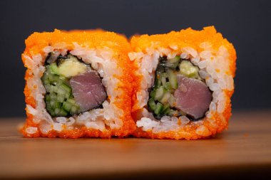 Koyu arka planda somon ve salatalık ile California rulo.