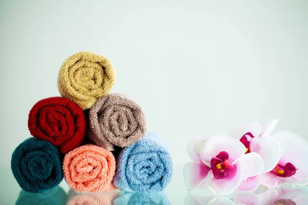 Toallas coloreadas y orquídea en mesa blanca con espacio de copia en el fondo del cuarto de baño — Foto de Stock