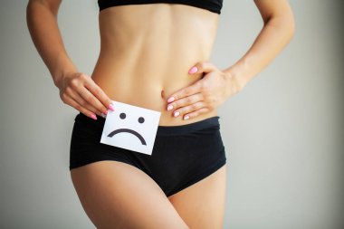 Kadın sağlığı. Kadın vücudu mide yakınındaki üzgün Smiley kartı tutan