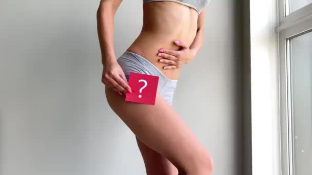 Salud. Mujer cuerpo en ropa interior con tarjeta de preguntas cerca del vientre — Vídeos de Stock