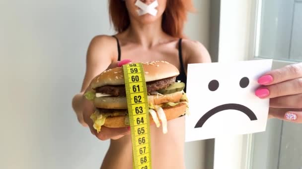 Dieta. Retrato de una mujer quiere comer una hamburguesa, pero una boca pegada, una noción de dieta, comida poco saludable, una voluntad en la nutrición — Vídeo de stock