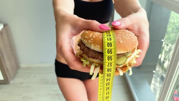 다이어트. 여자의 초상화는 햄버거를 먹고 싶어하지만, 접착 입, 다이어트의 개념, 건강에 해로운 음식, 영양의 의지 — 비디오