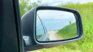 Yan aynada görünümü, araba güneşli bir günde köyde off-road hareket
