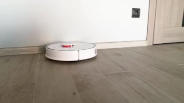 Akıllı Ev. Elektrikli süpürge robotu oturma odasında ahşap zeminde koşar.