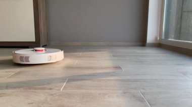 Akıllı Ev. Elektrikli süpürge robotu oturma odasında ahşap zeminde koşar.