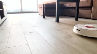 Akıllı Ev. Elektrikli süpürge robotu oturma odasında ahşap zeminde koşar.
