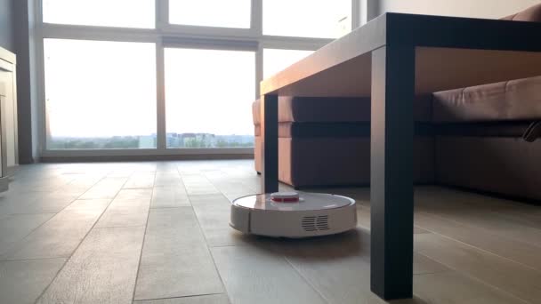 Een slim huis. Stofzuiger robot loopt op houten vloer in een woonkamer — Stockvideo