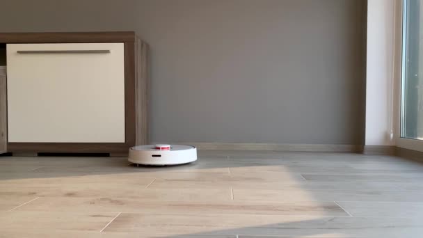 Akıllı Ev. Elektrikli süpürge robotu oturma odasında ahşap zeminde koşar. — Stok video