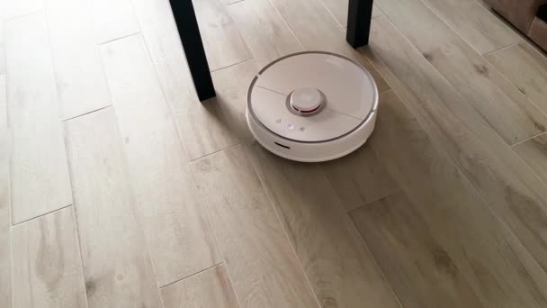 Casa Inteligente. Aspirador robot funciona en el suelo de madera en una sala de estar — Vídeos de Stock