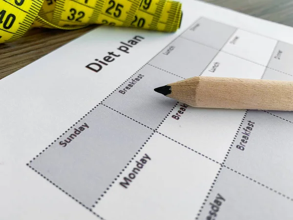 Diet plan concept. Measuring tape and diet plan on wooden background