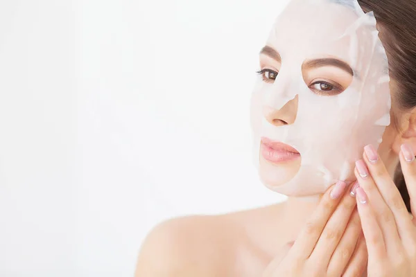 Wanita muda yang cantik mendapatkan masker tanah liat wajah di spa, berbaring dengan mentimun di mata — Stok Foto