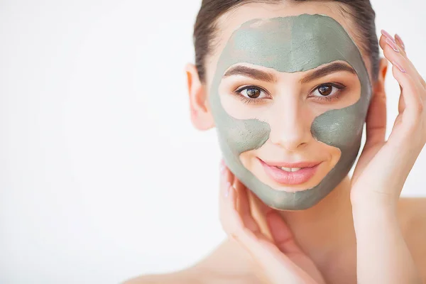 Cuidado com a pele. Mulher jovem com máscara de barro cosmético segurando pepino em seu banheiro — Fotografia de Stock