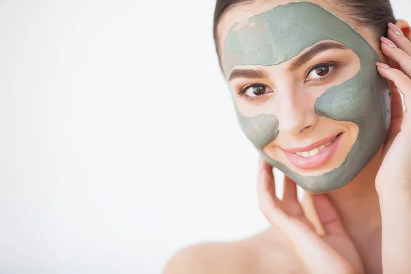 Cuidado com a pele. Mulher jovem com máscara de barro cosmético segurando pepino em seu banheiro — Fotografia de Stock
