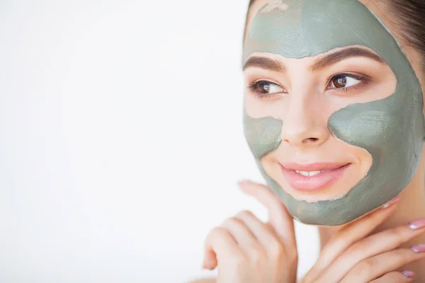 Cuidado com a pele. Mulher jovem com máscara de barro cosmético segurando pepino em seu banheiro — Fotografia de Stock