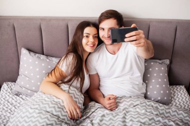 Genç çift selfie birlikte yatak odasında alarak gülümseyen