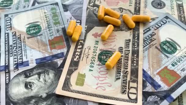 Medicina cara. Comprimidos de cores diferentes no fundo do dinheiro . — Vídeo de Stock