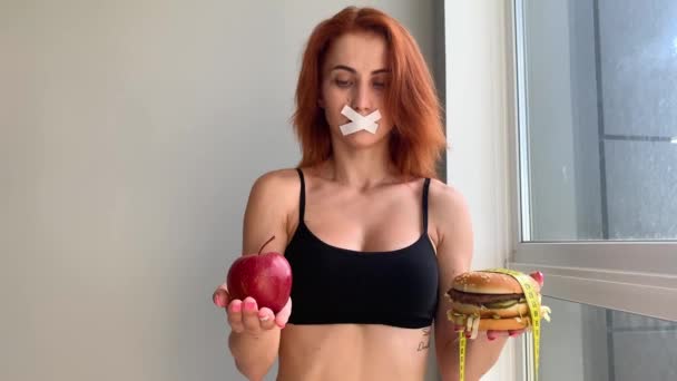 Dieta. Ritratto di donna vuole mangiare un hamburger, ma una bocca incollata, una nozione di dieta, cibo malsano, una volontà nella nutrizione — Video Stock