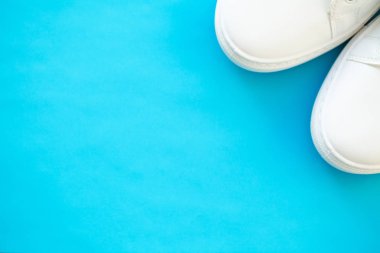 Mavi arka planda şık beyaz moda spor ayakkabıları.