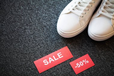 Gri arka planda indirimli yeni şık beyaz spor ayakkabı çifti.