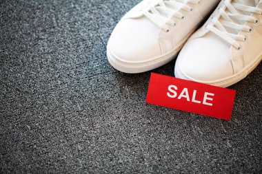 Gri arka planda indirimli yeni şık beyaz spor ayakkabı çifti.