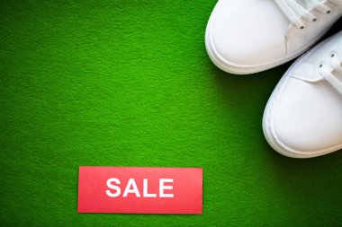 Yeşil arka planda indirimli yeni şık beyaz spor ayakkabı çifti.