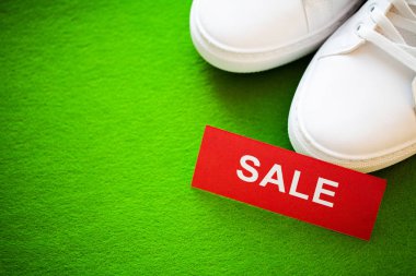 Yeşil arka planda indirimli yeni şık beyaz spor ayakkabı çifti.