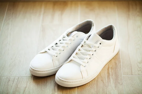 Par nya snygga vita sneakers på trägolv. — Stockfoto