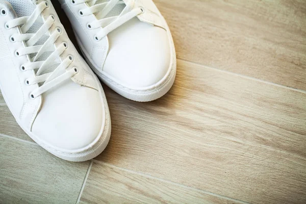 Par nya snygga vita sneakers på trägolv. — Stockfoto