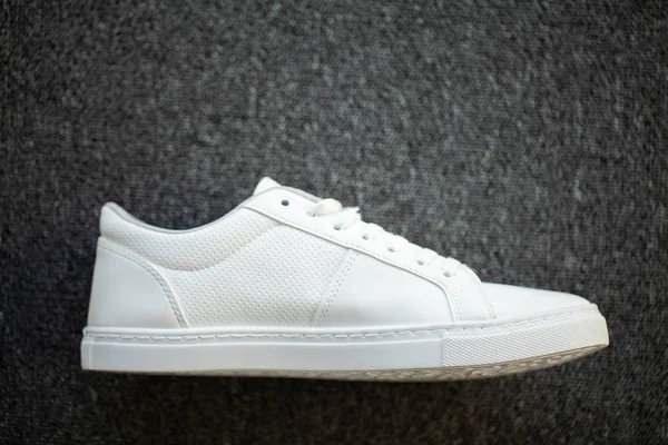 Nuova elegante sneaker bianca sul pavimento a casa . — Foto Stock