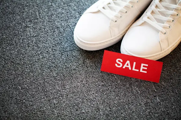 Gri arka planda indirimli yeni şık beyaz spor ayakkabı çifti.