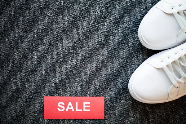 Gri arka planda indirimli yeni şık beyaz spor ayakkabı çifti.