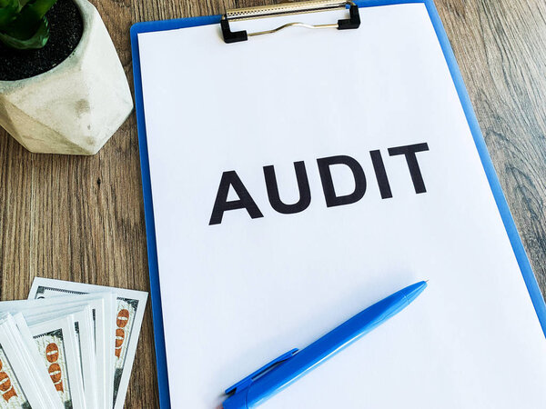 Clipboard with text audit on wood desk.